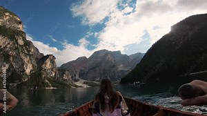 Young woman sitting on the edge of a wooden boat in Lake Braies, Dolomites. Tourist girl enjoys the alpine azure lake clear water fabulous nature of mountain green forest Italian Alps