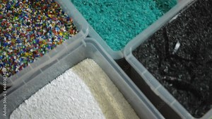 Live camera moves along boxes with sorted plastic garbage of different colors. Top view close-up shredded trash on recycling station indoors