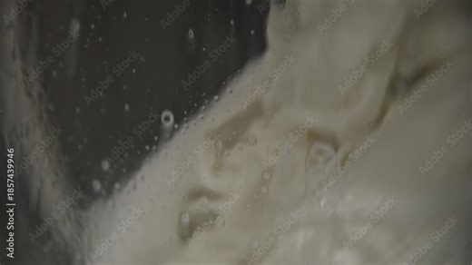 An automatic washing machine washes dirty white clothes. Washing clothes in a domestic washing machine. Close-up video of the spinning drum of a washing machine.