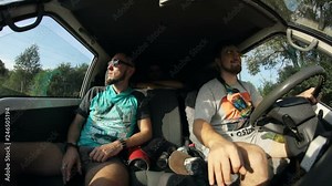 Happy man driving car with his friends smiling having fun and traveling together. Front view of a driver and passengers taking a trip at country road.
