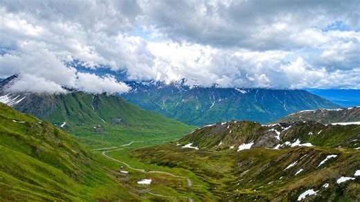Ein weites grünes Tal unter Alaskas Bergwolken