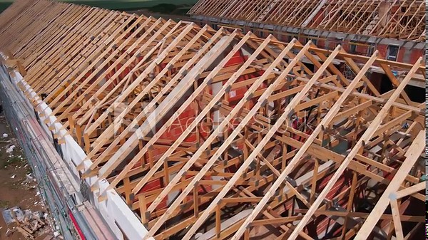 New house under construction, wooden truss system forming roof. Process of building project.