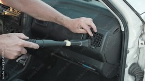 Man cleans, vacuums the car inside, old and dirty. Cleans the fan in the front panel of the vehicle.