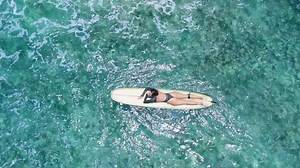 Woman on longboard in blue ocean. Drone view of woman during surfing