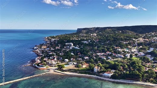 Azure bay waterfront aerial view, crystal water lapping against rocky cove, treelined streets and white