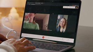 Right hand of Asian young man scrolling, two women on screen having call