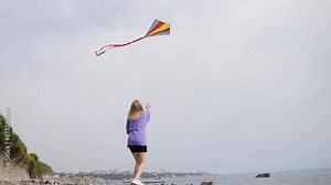 Young woman flying kite on beach in summer day. Happy woman has fun and remembers childhood