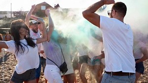 Cheerful people have fun splashing colorful powder, celebrate Holi festival in slow motion. Friends play with dry paint at hindu festival of spring, colours, love. End of covid pandemic isolation