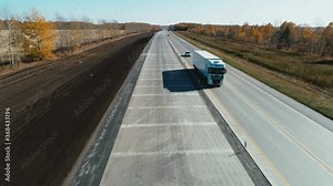Truck and cars go along the highway. Top view on the highway on a sunny day. Cars drive on an asphalt road. Autobahn. Aerial view of a highway passing through a field. logistics, transportation, cargo