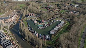 An aerial view of Campbell Wharf Marina and the moored barges on a sunny winter morning in Milton Keynes, Buckinghamshire, UK. The shot rotates left to right around the marina.