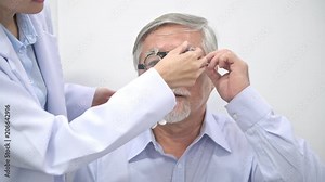 Happy senior man trying out his lens using Phoropter with a help of a nurse. Beautiful female nurse putting on phoropter to chinese man to test his eye sight. Zoomin shot. Eyecare concept.