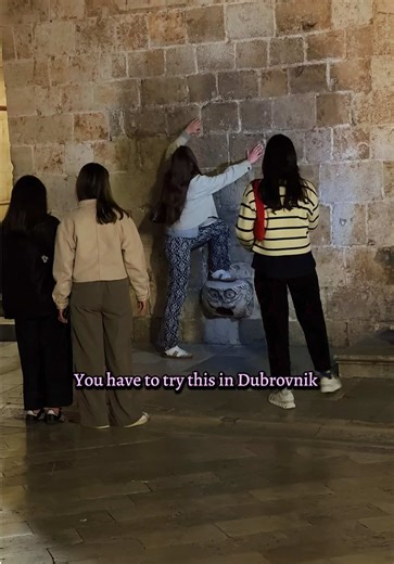The tradition is to stand on it facing the wall, then try to take off your shirt, turn around and put it back on, all while standing on the “stone owl”, also known as the mascaron. Good luck!! 🥰😍 #dubrovnik #maskeron #fyp #viral #oldtown @experiencedubrovnik @Grad Dubrovnik @croatiafulloflife