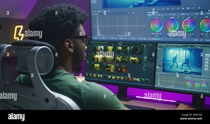African American video editor makes color grading, works at home office. Action movie footage and program interface on multi-monitor computer and big digital screen. Concept of film post production Stock Photo - Alamy