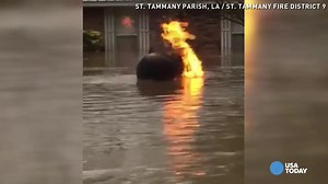Flaming propane tank floats through floodwater