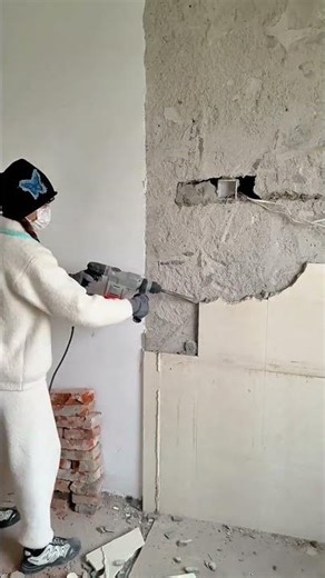Woman using powerful hammer drill to demolish old wall