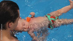 Newborn baby diving under water and making turn in the water. 4K