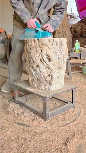 Worker cutting large tree stump using electric chainsaw outdoors