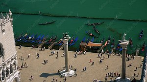 Columns of Saint Mark - Column of Lion and Saint Theodore of Venice, people walking between the columns near traditional venetian boats called gondolas.
