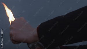 Hand of young protester Igniting Molotov Cocktail bottle HD close up storm clouds on background