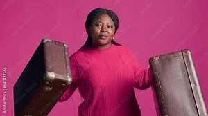 Female african american traveler with confidence proudly displays fashionable brown suitcases. Stunning black woman with vibrant smile grasps two pieces of luggage ready to travel in style.