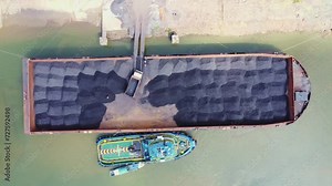 The process of loading coal onto barges using heavy transport cars