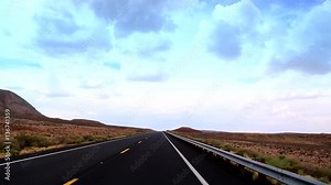 A car drives at Highway, cutting the desert of Arizona with and indescribable beauty. The road travels on painted desert, through a lava field and opens up to the State Mountain and Red Mountain.
