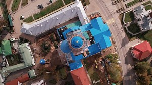 Top view of orthodox church with scaffolding surrounded by ancillary buildings and city blocks with stadium and parks
