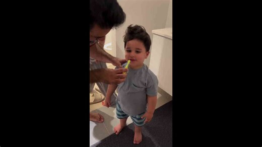 Child giggling while brushing teeth in Denmark