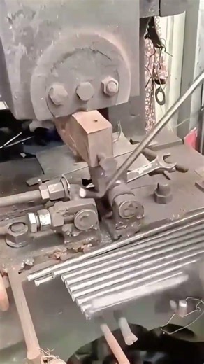 bending silver metal rods into uniform curved shapes using heavy duty industrial bending machinery