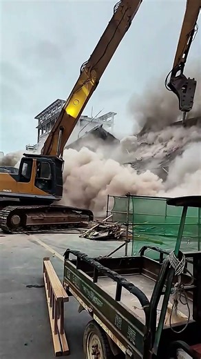 Dangerous powerful excavator operator high reach demolition excavator ripping down building