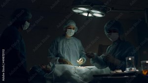 Medical team performing surgery in hospital room. Surgeon passing instruments.
