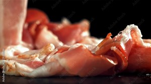 Fresh bacon falling on black background. Filmed on a high-speed camera at 1000 fps. High quality FullHD footage