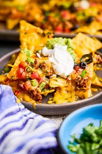 The ultimate nacho recipe! Crispy chips with melted cheese, ground beef, refried beans, and all of your favorite toppings. https://thestayathomechef.com/ultimate-nacho-recipe/ | Recipes