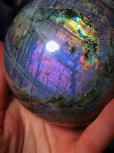 🖤 LABRADORITE SPHERE A STORMY VEIL 🖤 This Labradorite sphere is wrapped in natural fracture lines and smoky layers that create a moody, storm-cloud base , and then BOOM… electric flashes of blue, teal, gold, and soft violet break through when the light hits just right. Labradorite is known for its depth and movement, and this piece shows it beautifully. Every turn reveals a new shimmer hiding beneath the surface, making it a true statement sphere for all crystal lovers 🔥💜. #labradorite #labr