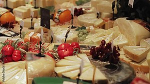 Variety and different types of swiss and french cheeses are on store counter showcase. Cheddar, parmesan on sale. Dairy products and food in shopping mall centre. Italian gouda, maasdam, camembert