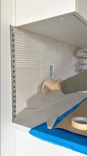 Installing hexagonal wall tiles with adhesive for a kitchen backsplash