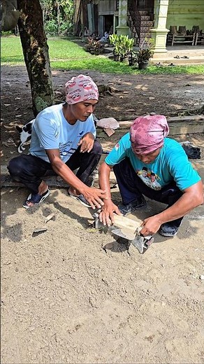 A senior teaches a beginner how to properly make concrete blocks.