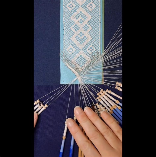 A way of finishing a bookmark at a point with a plaited ‘tail’. Work out through all pairs, pin then work back through only the first two pairs. The plait is worked by bunching the bobbins into four sections and tied off with a reef know using the outer pairs. Pattern designed by Julie Medland. Part of a series of 40 videos of bobbin lace stitches and techniques that we are sharing to support lacemaking as a legacy project for our 40th anniversary. Please see the earlier videos in this series fo