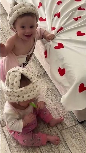 Twin babies playfully tussle with helmets in Simferopol, Russia