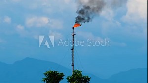 A flare stack burning off excess gas at an oil refinery with copy space in the hill background