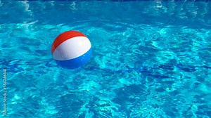Rainbow bouncy ball in pool. A view of bouncy rainbow ball in the clear swimming pool under sun.
