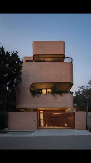 A sculpted urban home wrapped in soft curves 🧡 Designed on an approx. 30 ft × 60 ft plot, this G 2 residence has a built-up area of nearly 4,000 sq.ft. The house stands out with its rounded edges, monolithic massing, and earthy terracotta finish, giving it a calm yet powerful street presence. Deep curved balconies act as thermal buffers, reducing direct heat while creating shaded outdoor pockets. The minimal openings, warm lighting, and layered volumes ensure privacy, climate comfort, and visua