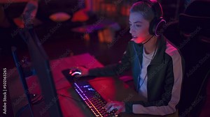 Excited Female Gamer Playing PvP RPG Strategy Video Game in Which Players Fight in a Tournament on Her Personal Computer. Room and PC with Neon Led Lights. Stylish Young Woman in Cozy Room at Home.