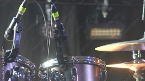 The sound technician tunes the drums and hangs up the microphones before the concert