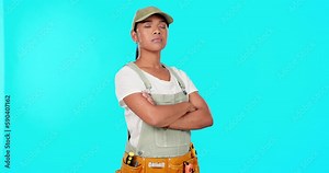 DIY, maintenance and a contractor woman on a blue background in studio standing with her arms crossed. Portrait, serious and home improvement with a young female handyman ready for construction