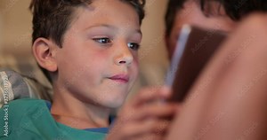 Handsome young boy using tablet device at night. Child multi-tasking, watching TV and playing game