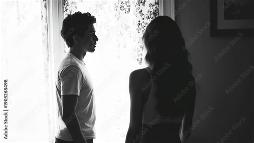 Dramatic black and white silhouette of a young couple having a difficult conversation in a bedroom