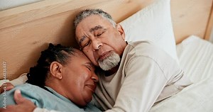 Love, sleep and a senior couple in bed together in the morning to relax on a weekend during retirement. Hug, home or bedroom with an elderly pensioner man and woman resting for peace or quiet