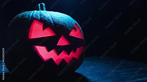 Spooky Halloween jack o lantern with glowing scary face in dark. Halloween concept. Shining Jack-o'-lantern. Happy Halloween. Illuminated face. Close-up in 4K, UHD