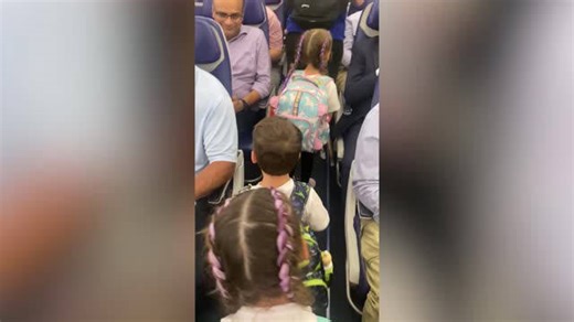 Young boy excitedly displays his new backpack to fellow passengers on flight